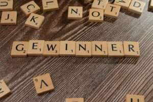 Scrabble tiles forming the word 'Gewinner' meaning winner on a wooden table.